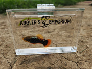 Small fish in a clear container with 'Angler's Emporium' branding on a natural background