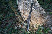 black fishing rod leaning against a tree