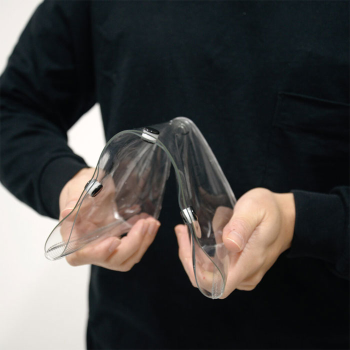Person holding a clear plastic object against a plain background