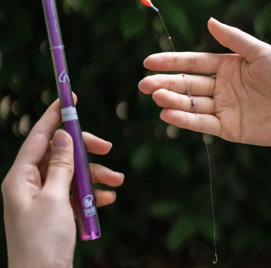 Person holding a purple fishing rod with a blurred background