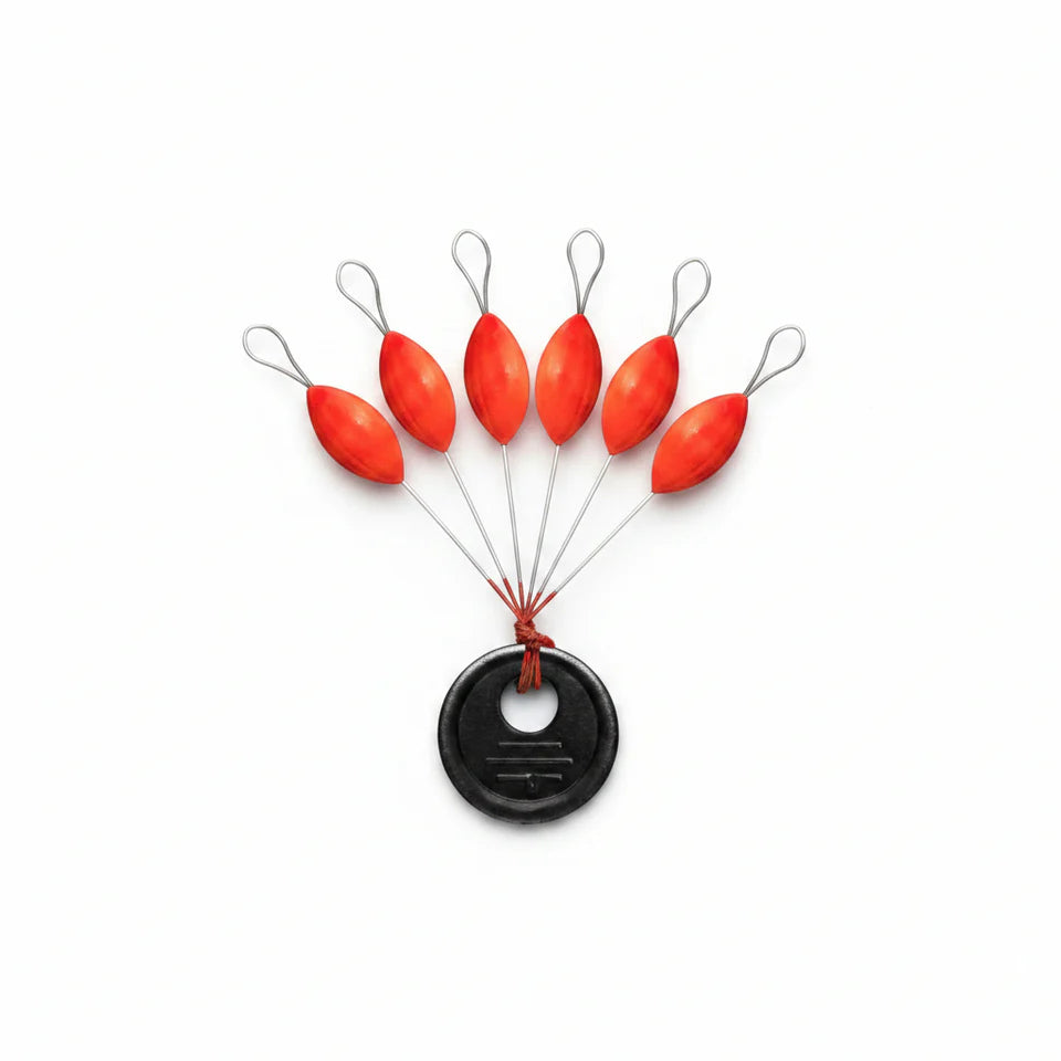 Set of red fishing floats attached to a black weight on a white background